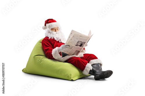 Santa Claus sitting on a bean bag and and reading a newspaper