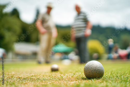 A focused image of a lawn bowling game, showcasing a close-up of a bowling ball on grass with blurred players in the background.