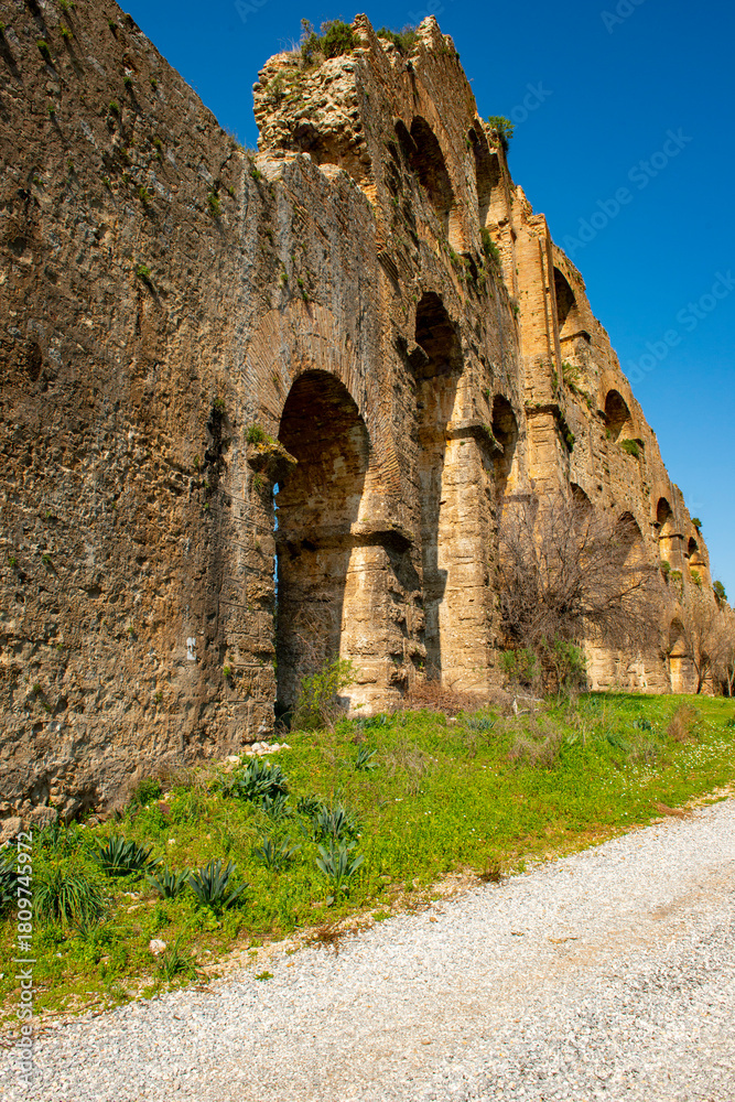 Fototapeta premium The Theatre and Aqueducts of the Ancient City of Aspendos is located in Southern Turkey, in the ancient Pamphylia region by the Eurymedon (Köprüçay) river. The acropolis lies about 60 m. above sea