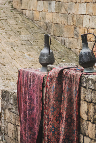 Antique jugs and carpets near the walls of an ancient stone fortress