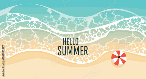 An aerial view of a beach with the words HELLO SUMMER written on the foamy waves and a red and white umbrella on the sand.