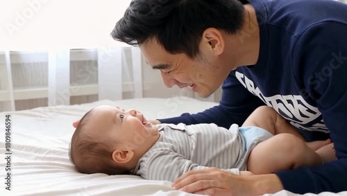 Happy father playing with his adorable baby on the bed at home, bonding and creating beautiful memories together.
