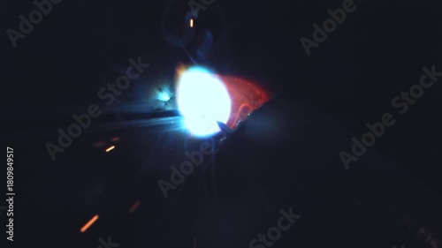 Bright welding light illuminates the dark workshop as sparks fly and metal fuses under intense heat, macro extreme close-up.