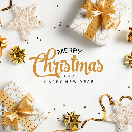 Merry Christmas & Happy New Year in white background with gifts wrapped in golden ribbon, & ornaments in flat lay top view