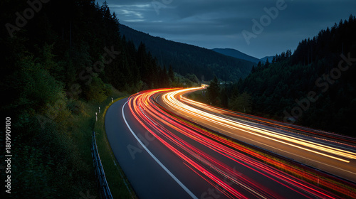 A winding road at night with car light trails creates a sense of movement