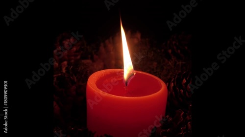 Warm glow of an orange candle flickering in a dark room creates a cozy atmosphere