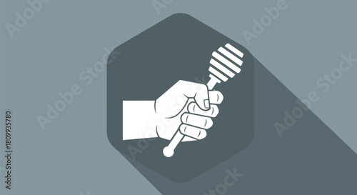 Hand holding a honey dipper with long shadow