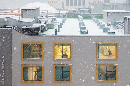 Illuminated windows of a building facade during snowfall