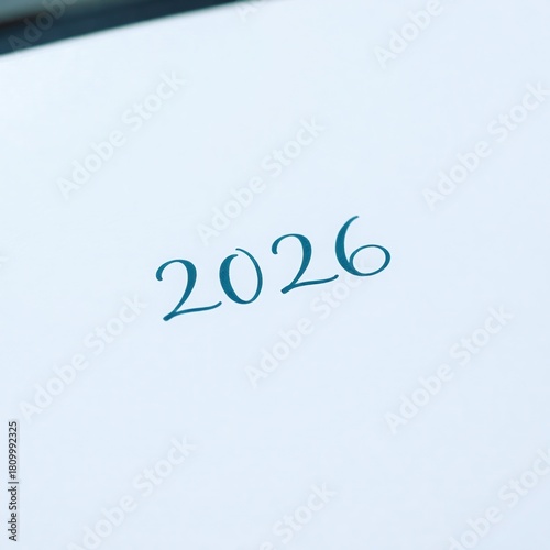 Pale page with teal calligraphic 2026 positioned slightly above center, tilted gently upward to the right