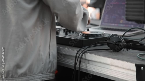 DJ who controls the mixer during an outdoor performance. Close-up of the audio equipment used, laptop and headphones