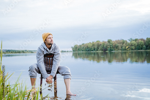 man enjoying peaceful water view, individual dressed casually experiencing calmness near serene water body, person in relaxed clothing immersing in quiet and peaceful lakeside environment