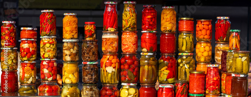Tableau sur toile Assorted pickled vegetables in jars on a market stall with bright colors and gla