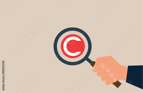 Hand with magnifying glass and copyright symbol. Intellectual property and legislation