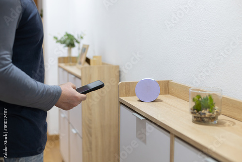 person controls smart wireless device with cell phone at home