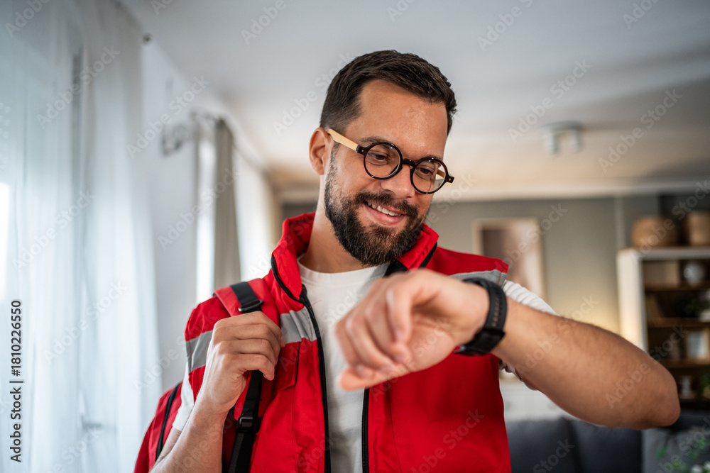 Fototapeta premium Paramedic man checking smartwatch during home visit consultation