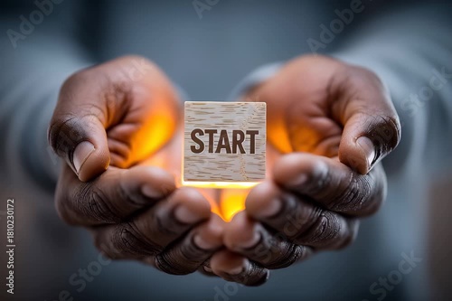 Wooden cube with start word glowing light warmly held in human hand symbolizing new beginning motivation concept and hands holding warm light gently