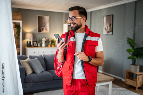 Paramedic man using smartphone wearing red uniform