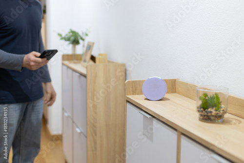 person controls smart wireless device with cell phone at home