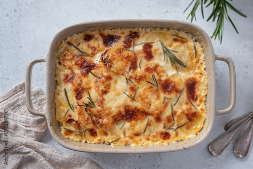 Creamy potato gratin topped with golden cheese and fresh herbs baked to perfection in a rustic dish