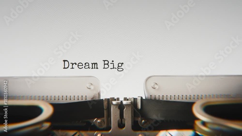 Old mechanical typewriter typing Dream Big Daily in a close-up view, with metal letters striking the white paper.