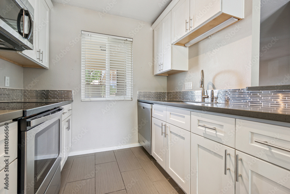 Fototapeta premium A kitchen with white cabinets, stainless steel appliances, and a sink