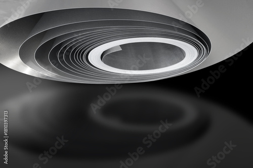 a silver aluminum roll glowing with a soft shadow effect on a dark background. twisted thin metal