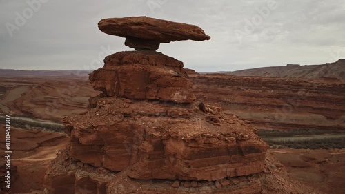 Aerial fly by past Hat Rock near Mexican Hat, UT with overcast skies