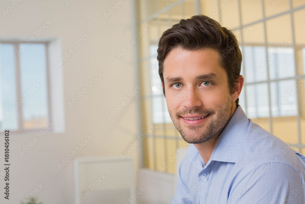 Obraz premium Man sitting at office in blue button-down shirt by large window with glass partition and plant