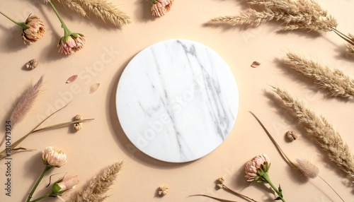 Dry natural grass, leaves and flowers frame with white marble podium, beauty and fashion concept mock up on beige background flat lay, top view, copy space