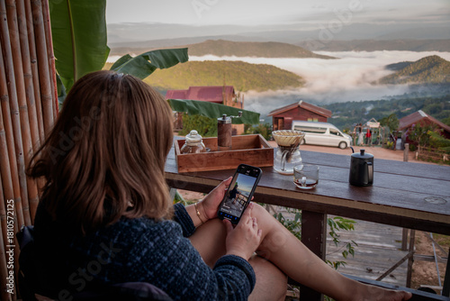 Woman Using Phone with Mountain View and Coffee