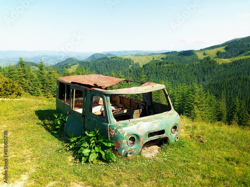 Abandoned rusty minibus overgrown in mountains