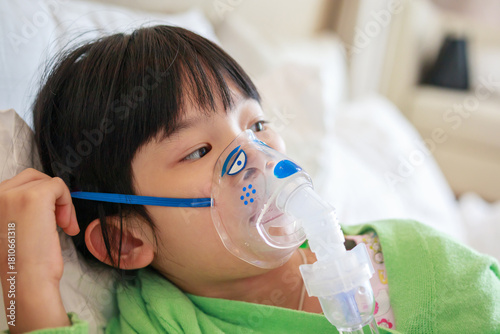 Sick little asian girl inhalation with nebulizer for respiratory treatment