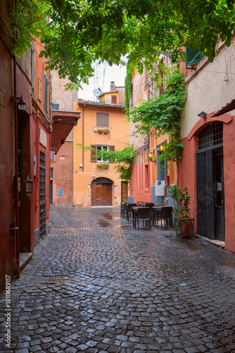 Narrow cobblestone street with colorful facades and outdoor seating in Trastevere, Rome, Italy