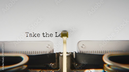 Old mechanical typewriter typing Take The Lead in a close-up view, with metal letters striking the white paper.