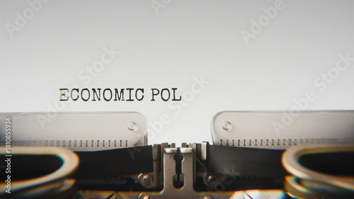 Old mechanical typewriter typing Economic Policy in a close-up view, with metal letters striking the white paper.