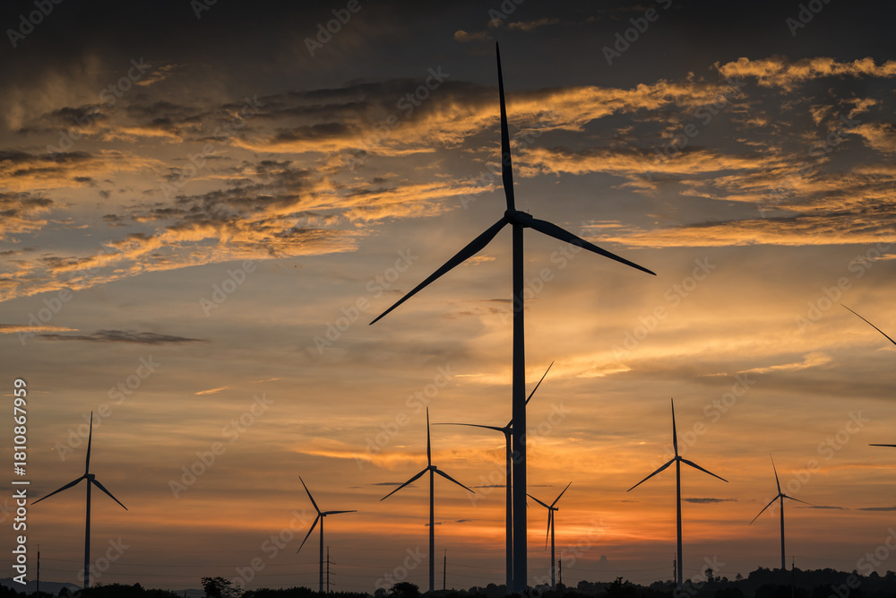 Obraz premium Electricity generating station, Wind turbines power generator in agricultural fields at sunset, Alternative Energy Windmill Farm, Clean energy concept.