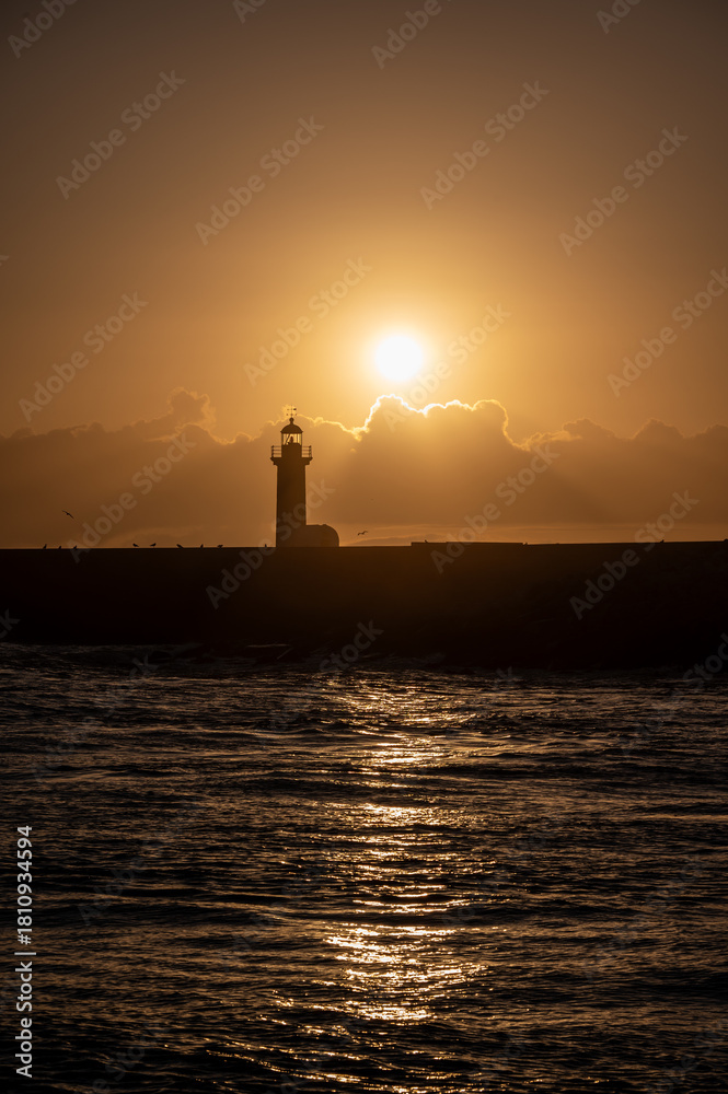 Fototapeta premium Felgueiras lighthouse on breakwater at mouth of Douro River in Porto, Portugal at sunset.