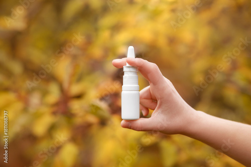 Tableau sur toile Nasal Spray in Hand in Autumn Fall Leaves Background as Necessary Help for Respiratory Diseases and Allergies