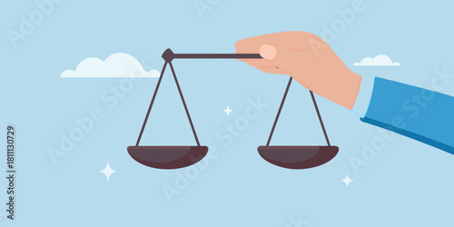 Hand holding scales of justice against a light blue sky background