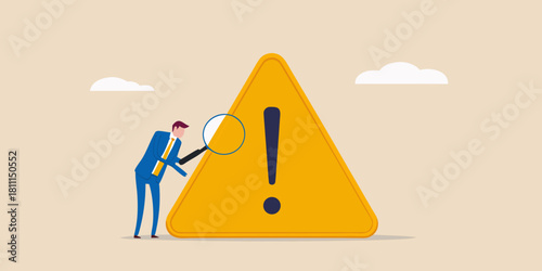 Businessman inspecting warning sign with magnifying glass risk management concept