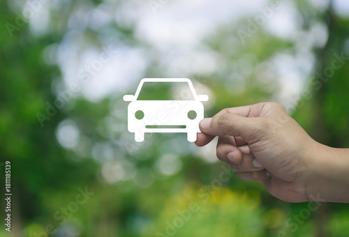Hand holding car flat icon in fingers over blur green tree in park, Business transportation service concept