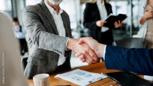 Confident handshake closes a deal in bright office, clean sleeves and polished table with genuine smiles crafting trustworthy business partnership visuals.