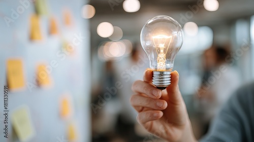 Bright idea sparking innovation as hand holds glowing lightbulb in creative meeting for brainstorming solutions and project planning for success