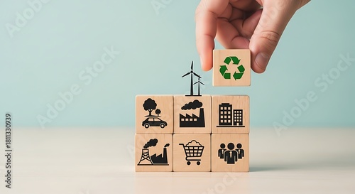 Hand placing a recycling symbol cube on top of blocks with ecofriendly icons, representing sustainability and green energy