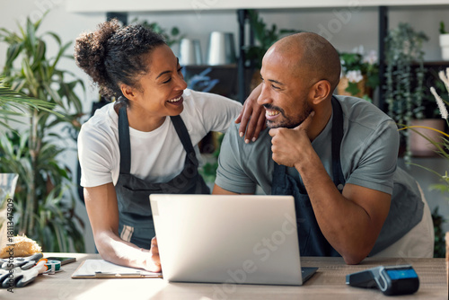 Entrepreneurs working together in a plant store with laptop and aprons