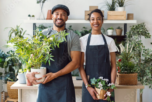 Entrepreneur and seller with apron holding plants in indoor plant store