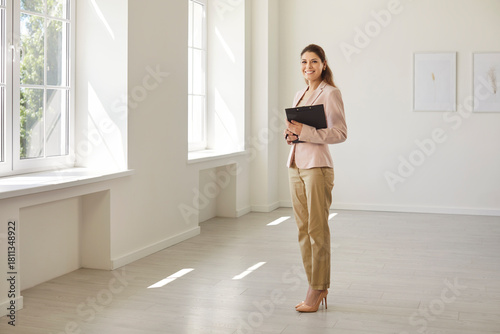 Foto Happy successful realtor, smiling female real estate agent carrying clipboard wi