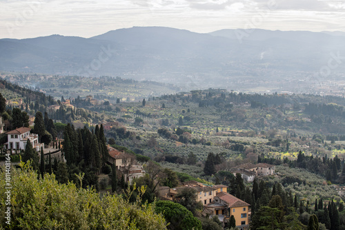 Panoramic view of Florence, Italy, seen from Fiesole in the evening haze, featuring Brunelleschi's dome of the Cathedral of Santa Maria del Fiore and city rooftops.