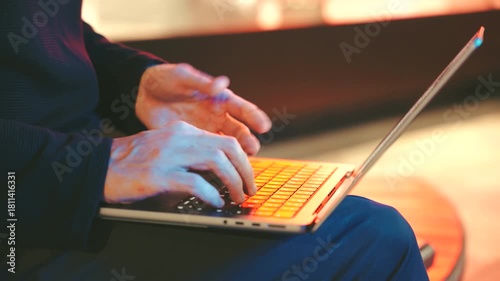 Man hands typing on a modern laptop, streetlights at night. The background is blurred, creating a cinematic effect.