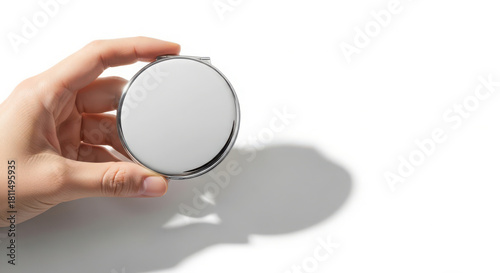 Close-up of hand holding a sleek silver pocket mirror on clean white background
